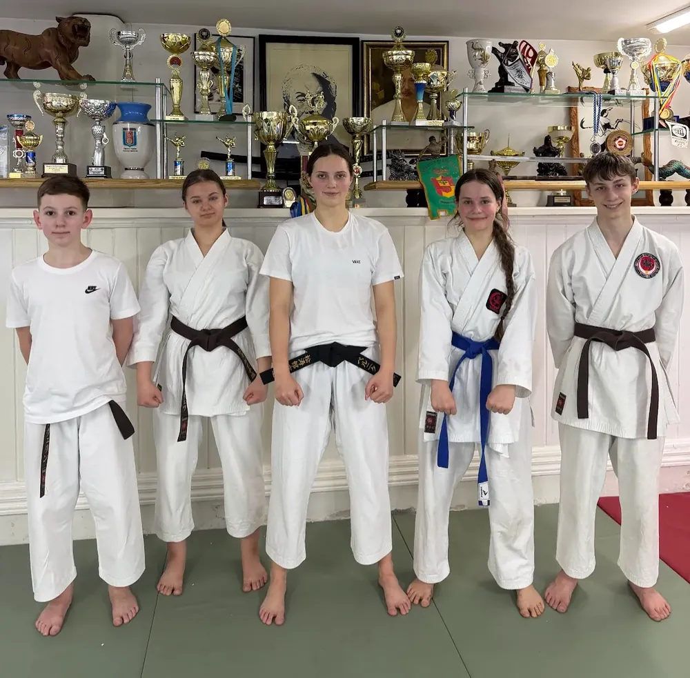 Ученики DZEN KARATE CLUB с цветными поясами в зале с кубками