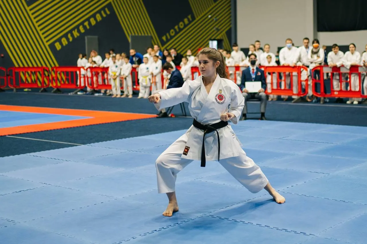 Спортсменка з чорним поясом виконує ката на татамі