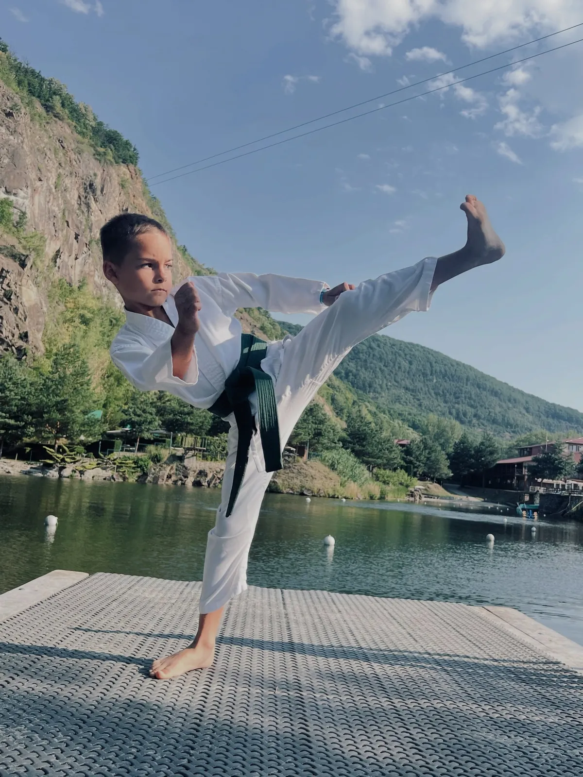 Ученица DZEN выполняет удар ногой у озера